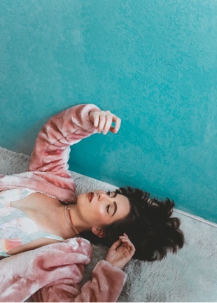 Harper laying down on the floor next to a teal wall