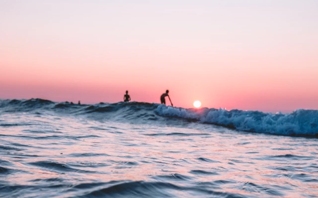 People in the distance surfing in ocean waves