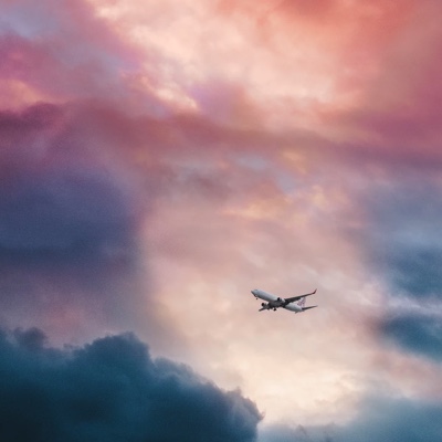 airplane flying through a cloudy sky at sunset